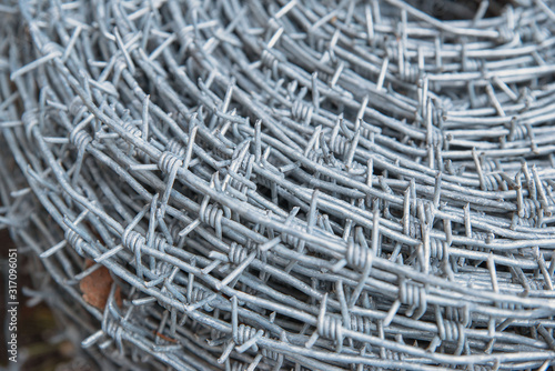 Close up on a pile roll of shiny new barbed wire for fence fencing. Security protection law enforcement. Prison jail criminal offense locked up