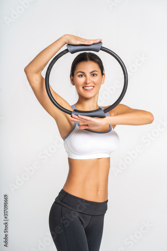 Sporty attractive woman doing pilates exercise for arms and shoulders with ring. © Mironifamily