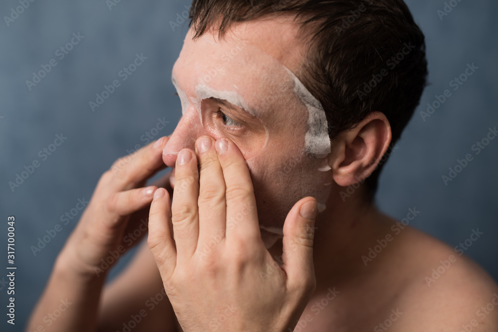 Obraz premium A young man 35-38 years old with a cosmetic moisturizing mask on his face