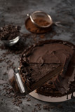 Raw chocolate cheesecake on dark grey background. Healthy organic dessert pie. Cacao and chocolate around