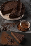 Raw chocolate cheesecake on dark grey background. Healthy organic dessert pie. Cacao and chocolate around