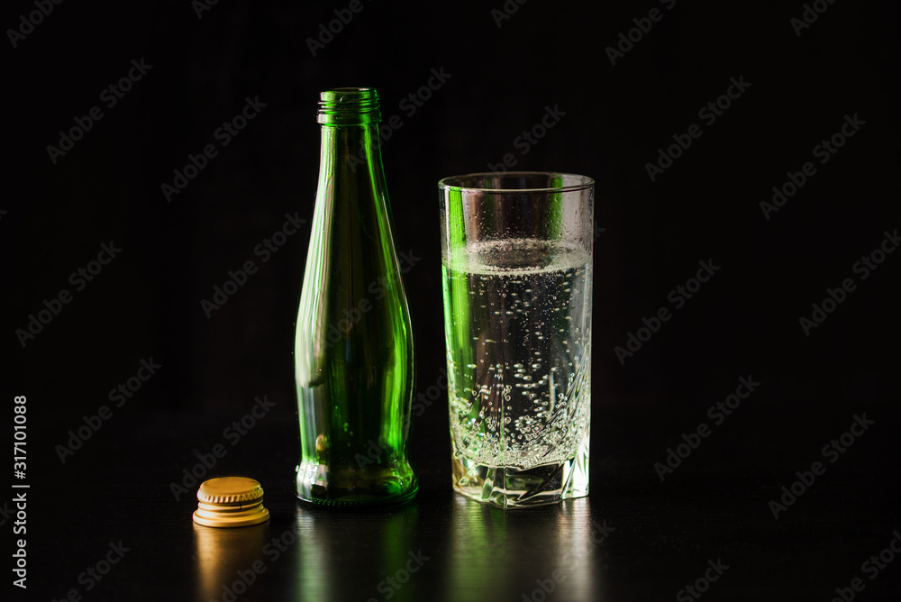 Gassed water in a glass on a black table and black background.