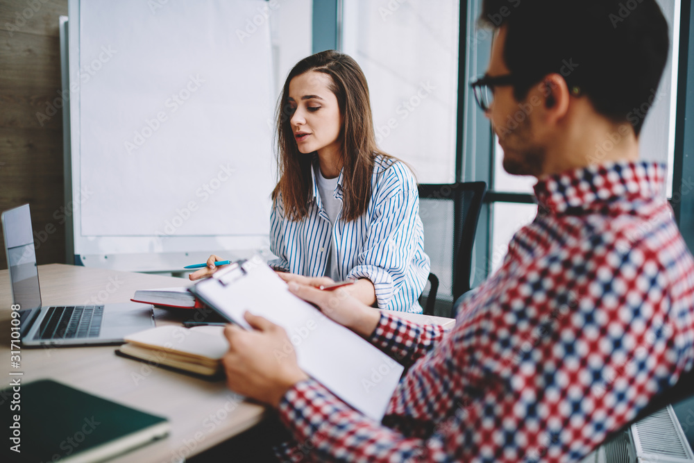 Fototapeta premium Male and female colleagues analyzing business plan together at office