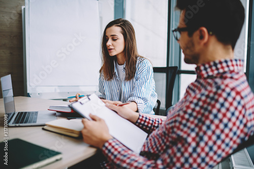 Male and female colleagues analyzing business plan together at office