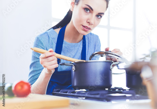 Cooking woman in kitchen with wooden spoon