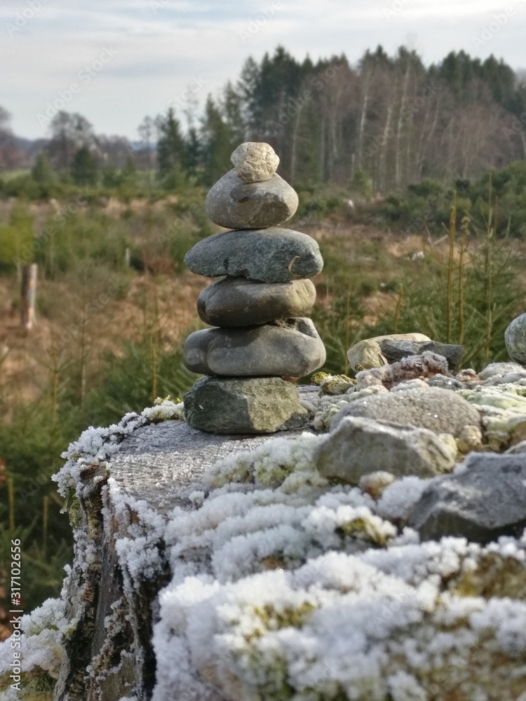 Steinmännchen auf verschneitem Baumstumpf Steinmännchen auf verschneitem Baumstumpf
