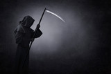 Grim reaper with scythe in the dark