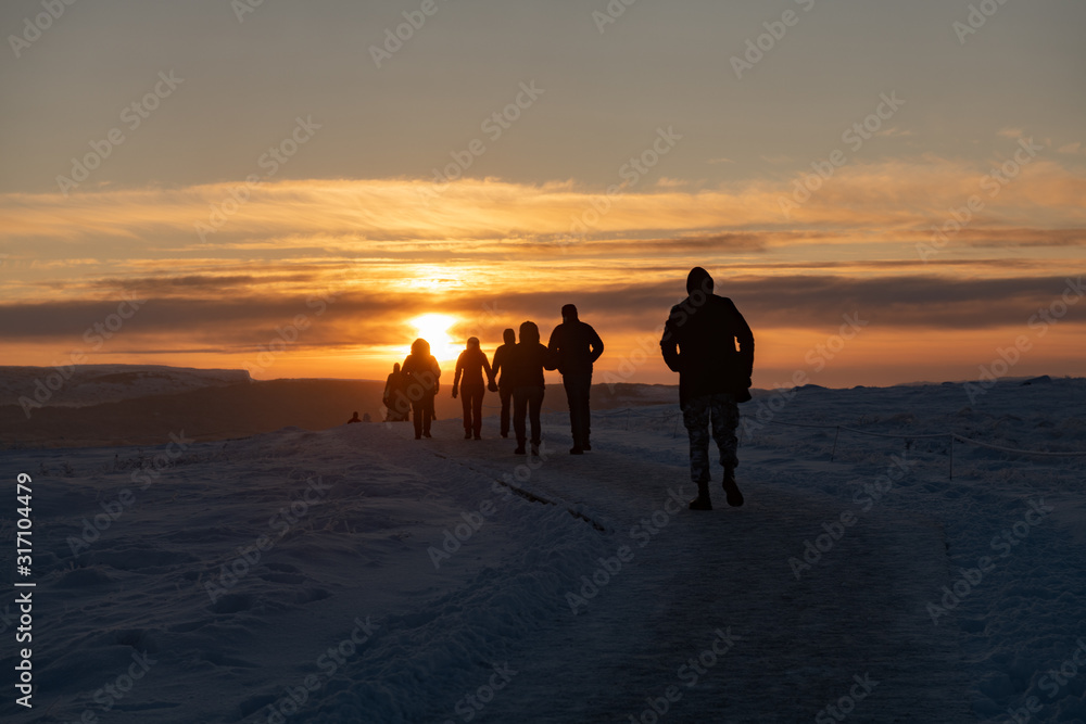 Silhouette of group of tourists walking through snow at sunset in Iceland Silhouette of group of tourists walking through snow at sunset in Iceland