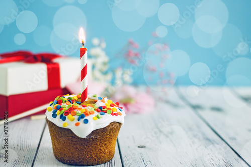Delicious birthday cupcake  with a candle on a blue background