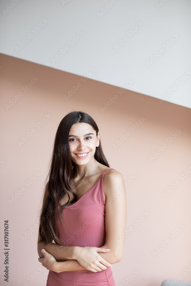 Beautiful woman with long hair is smiling indoors on wall background. Beautiful woman with long hair is smiling indoors on wall background.