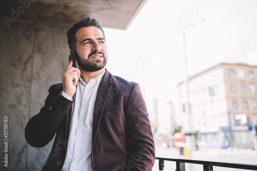 Pensive boss talking on smartphone on balcony in city