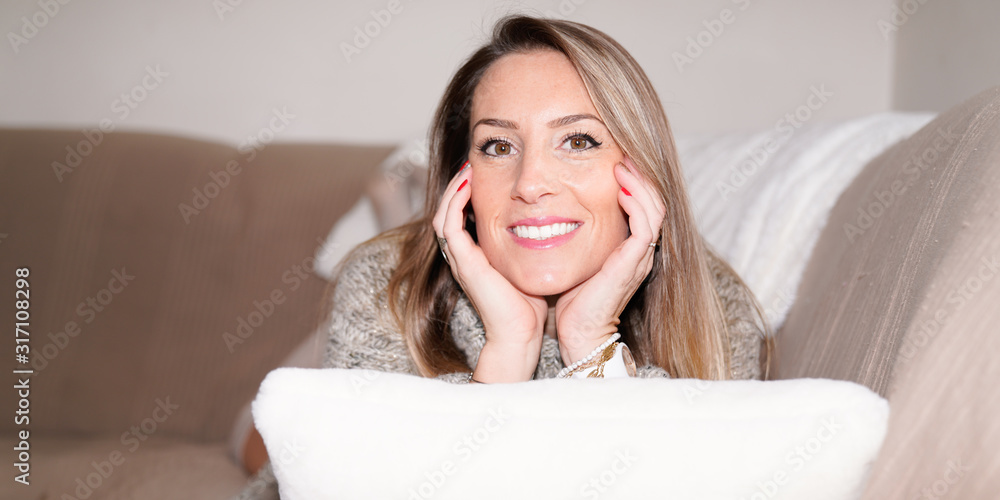 Woman relaxing at home couch lying in sofa hands on chin beautiful smile Woman relaxing at home couch lying in sofa hands on chin beautiful smile