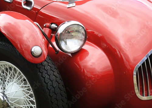 front of red race car showing headlamp and part of wheel