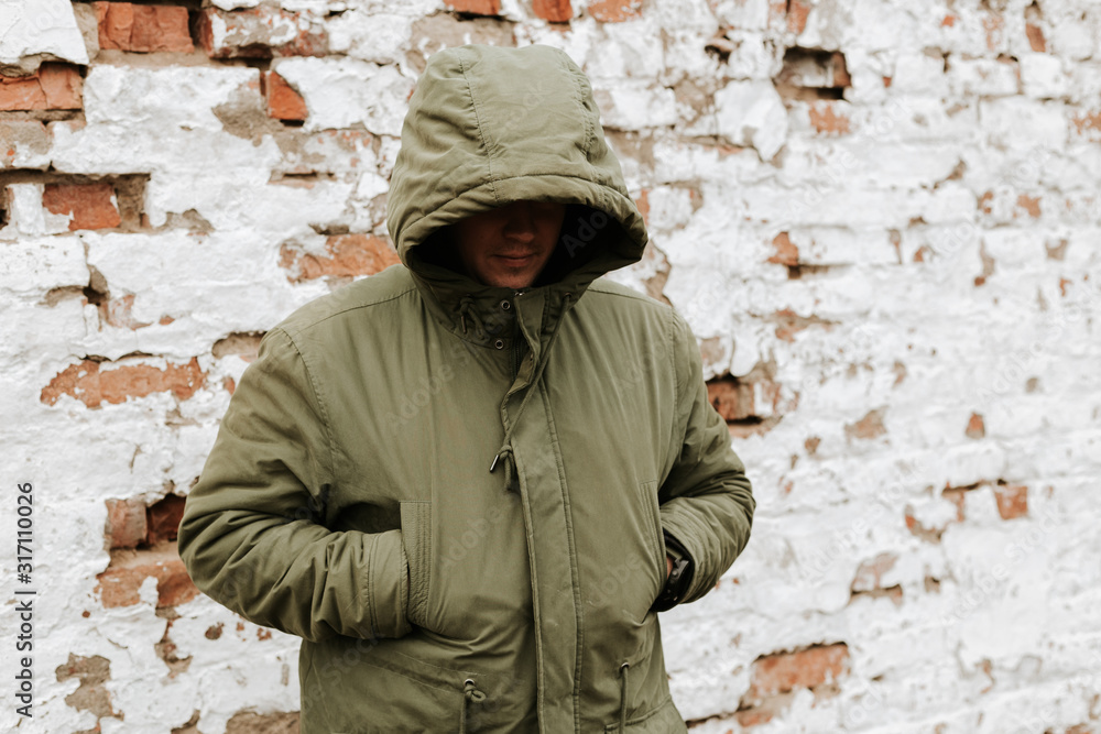 Guy with a hood over his head, his face is not visible. The concept of drugs, theft and crime. Red with White Retro Grunge Brickwall Backdrop Guy with a hood over his head, his face is not visible. The concept of drugs, theft and crime. Red with White Retro Grunge Brickwall Backdrop