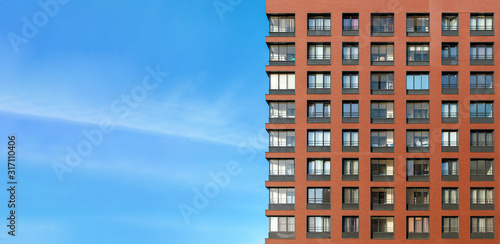 The modern brick facade of a high-rise building against the blue sky