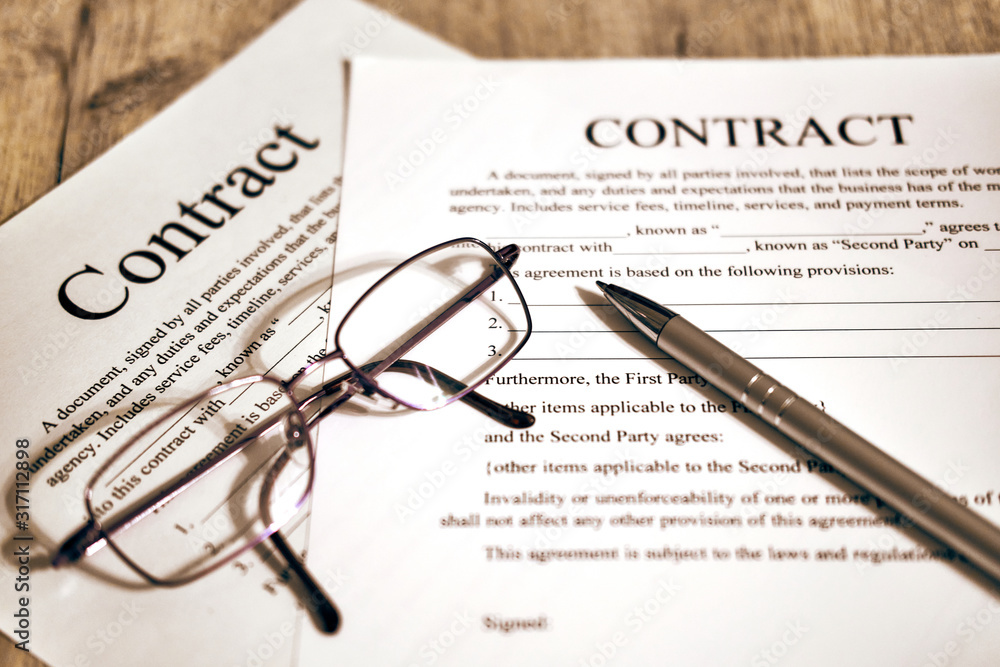 Contract sheet with glasses and a pen on a wooden background Contract sheet with glasses and a pen on a wooden background