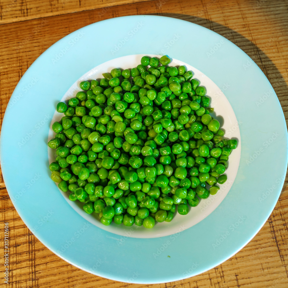 Fresh green peas in earthenware plate on wooden background, top view. Rustic table background Fresh green peas in earthenware plate on wooden background, top view. Rustic table background