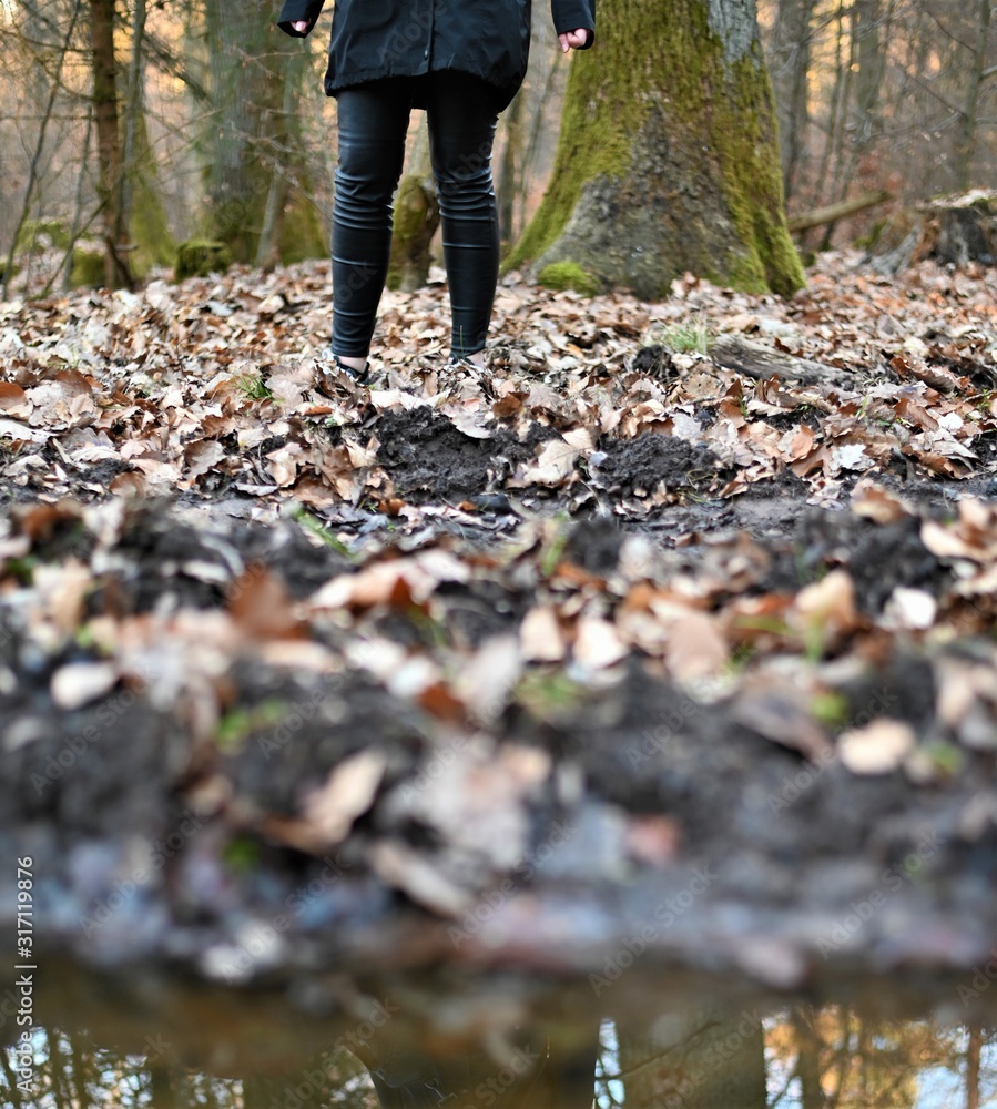Frau auf Spaziergang im Herbst im Wald mit matschigem Boden und Laub Frau auf Spaziergang im Herbst im Wald mit matschigem Boden und Laub