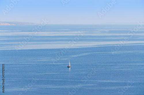 Volga river near Ulyanovsk, Russia. Blue background of sky and water with a sail in the distance © GalinaB