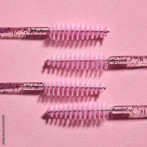 Minimalism brush for combing eyelashes on pink background. beauty fashion.Patern photo