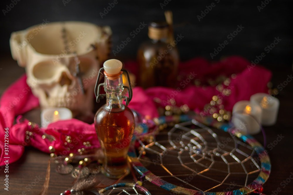 Scary still life with potions, skull, mortar, vintage bottles and candles on witch table. Halloween or esoteric concept.