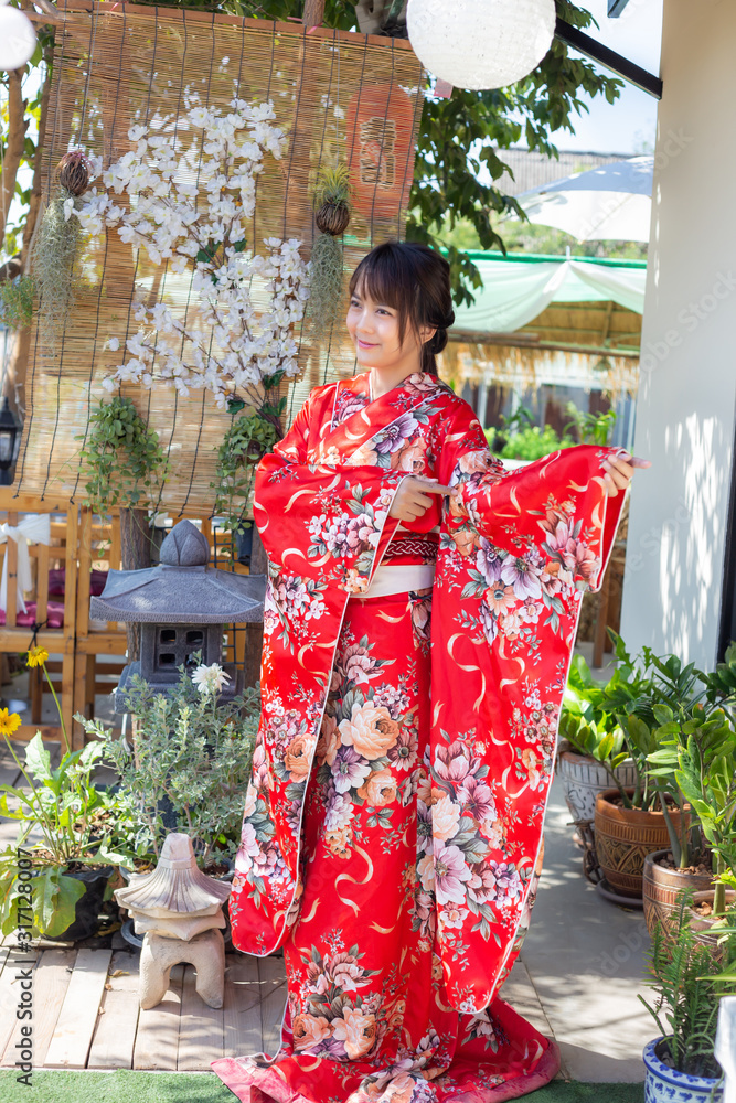 The girl is wearing a red traditional kimono, which is the national dress of Japan The girl is wearing a red traditional kimono, which is the national dress of Japan