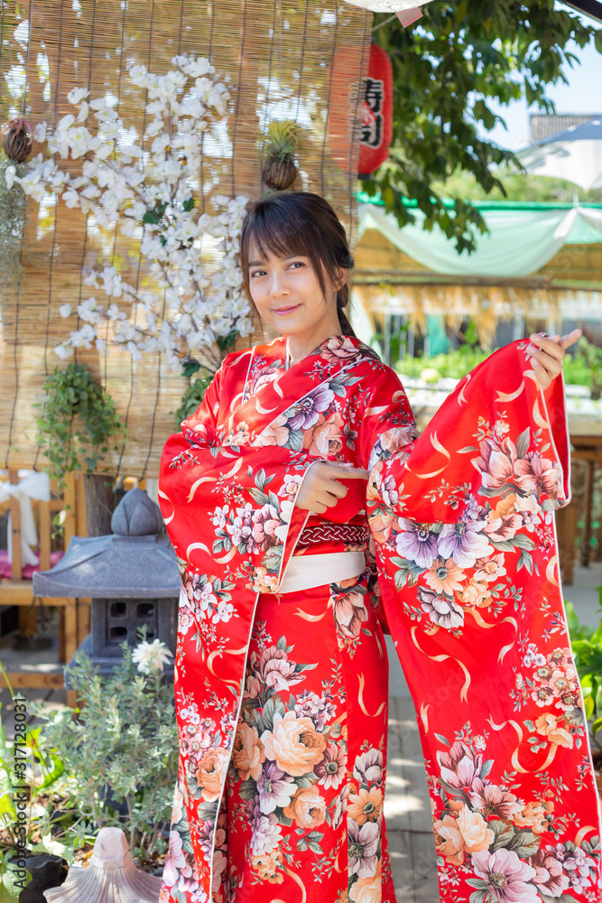 The girl is wearing a red traditional kimono, which is the national dress of Japan The girl is wearing a red traditional kimono, which is the national dress of Japan