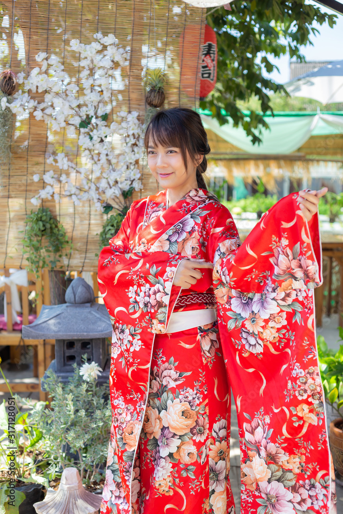 The girl is wearing a red traditional kimono, which is the national dress of Japan The girl is wearing a red traditional kimono, which is the national dress of Japan