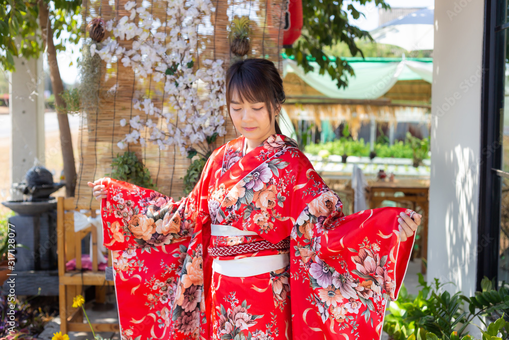 The girl is wearing a red traditional kimono, which is the national dress of Japan The girl is wearing a red traditional kimono, which is the national dress of Japan