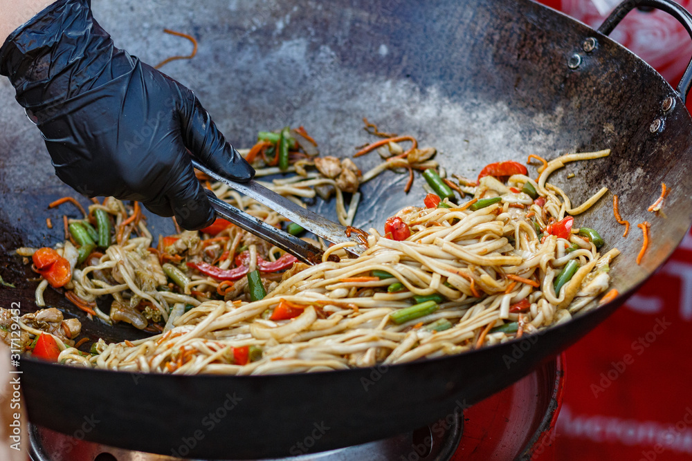 chef cooks Chinese noodle wok at street food festival Photos | Adobe Stock