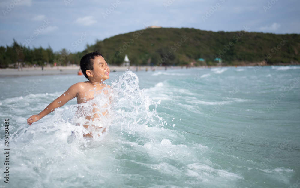 Boy playing  on sandy beach.  Happy kid on vacations at seaside on summer holidays. Children in nature with sea, sand and blue sky.