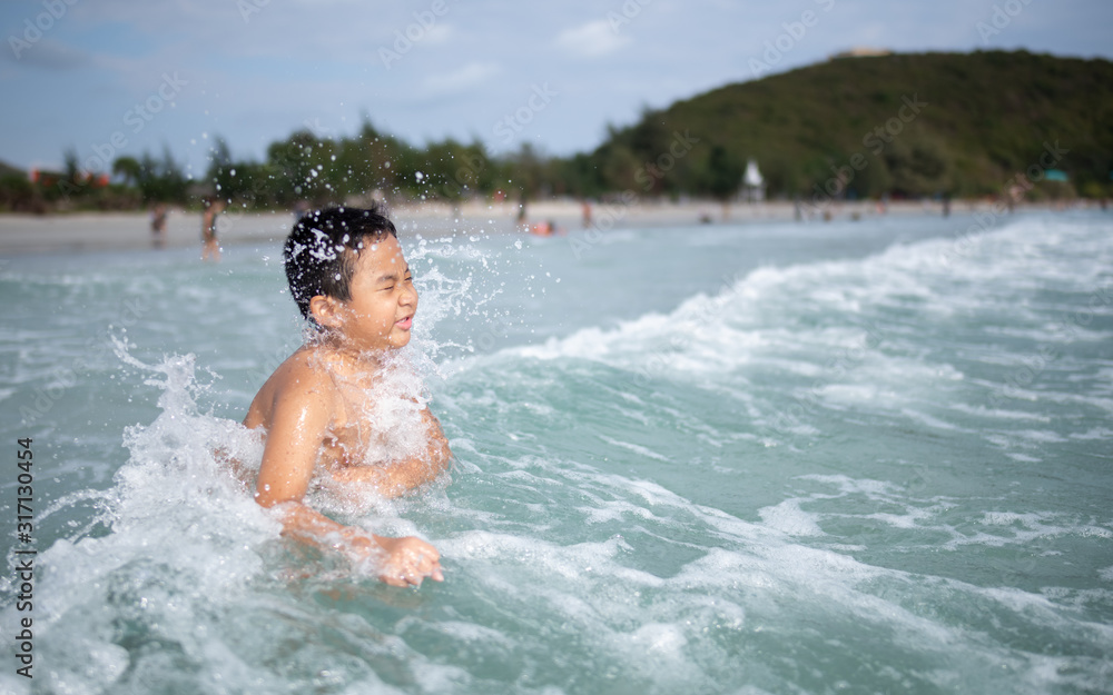 Boy playing  on sandy beach.  Happy kid on vacations at seaside on summer holidays. Children in nature with sea, sand and blue sky.