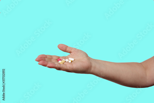 female hand holds out, offering, a handful of colored pills and capsules, close-up, color background, copy space, concept of medical care, treatment photo