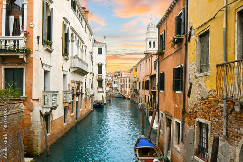 A colorful sky matches the colors of the medieval walls and canal in the historic center of Venice, Italy.