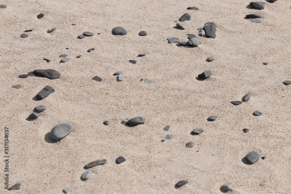 Small stones and pebbles are scattered on the brown-yellow sand Small stones and pebbles are scattered on the brown-yellow sand