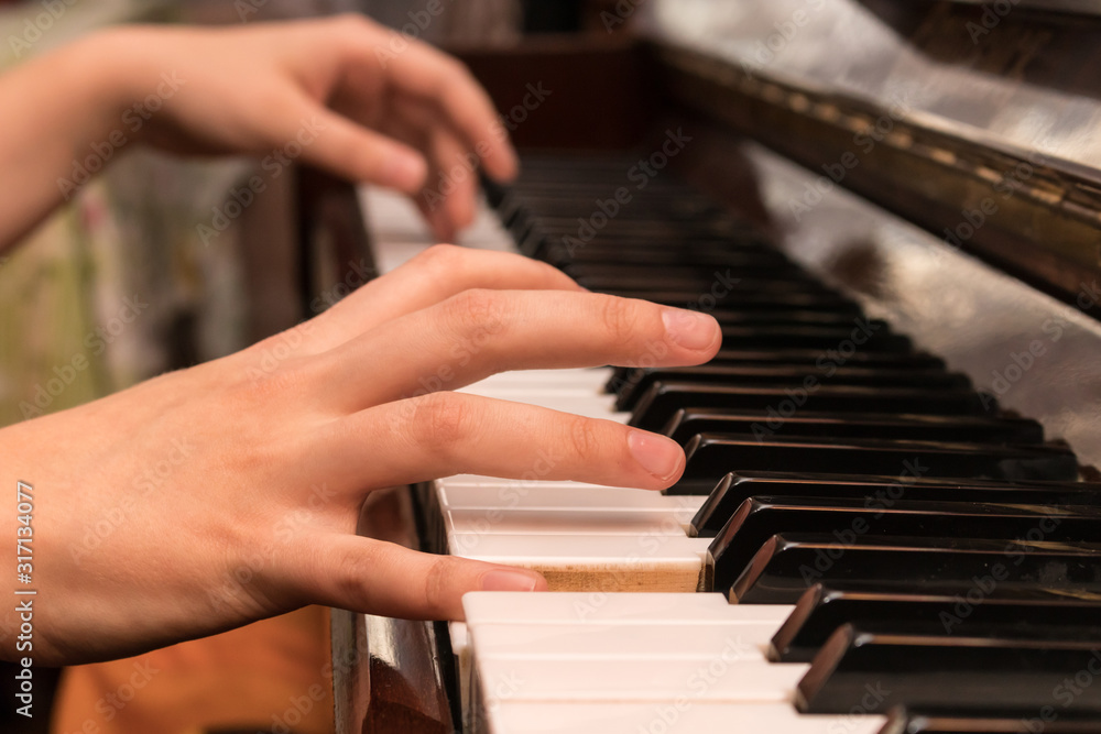 Hands of a girl playing the piano close-up