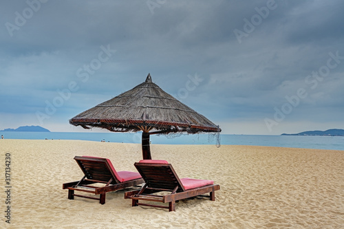 Fototapeta Naklejka Na Ścianę i Meble -  Straw parasol with two loungers at the tropical beach 