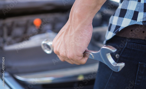 A man with a wrench in his hand to fix the car
