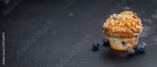 Fresh made Blueberry Muffins on a slate slab (close-up shot; selective focus)