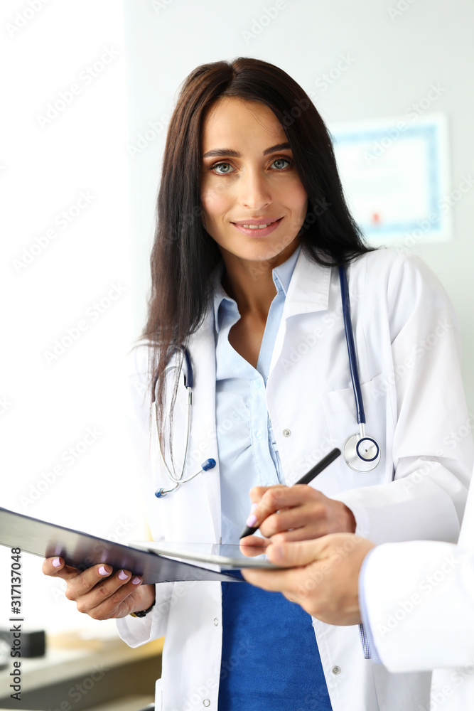 Smiling cheerful female GP making electronic notes in tablet pc portrait Smiling cheerful female GP making electronic notes in tablet pc portrait