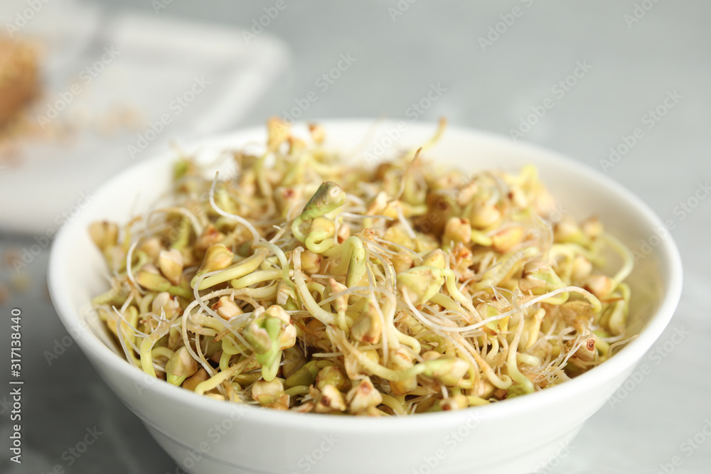 Bowl with sprouted green buckwheat on light grey table, closeup Bowl with sprouted green buckwheat on light grey table, closeup
