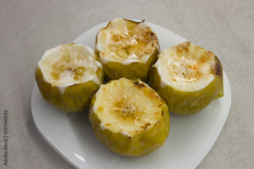 dessert dish: baked four apples with syrup on a white plate close-up dessert dish: baked four apples with syrup on a white plate close-up