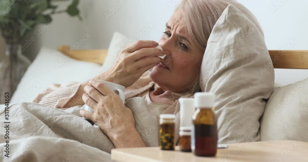 Ill old mature woman sneeze got flu sit on bed Ill old mature woman sneeze got flu sit on bed