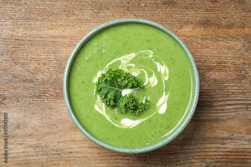 Tasty kale soup on wooden table, top view