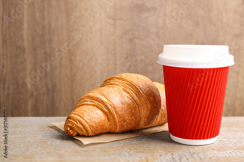 Tasty fresh croissant and drink on wooden table