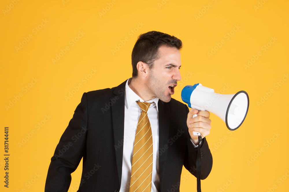 Portrait of a handsome businessman wearing white suit and tie while using megaphone, screaming with yellow background. Portrait of a handsome businessman wearing white suit and tie while using megaphone, screaming with yellow background.