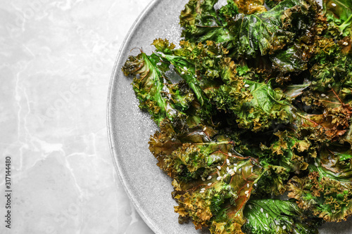 Tasty baked kale chips on light grey marble table, top view