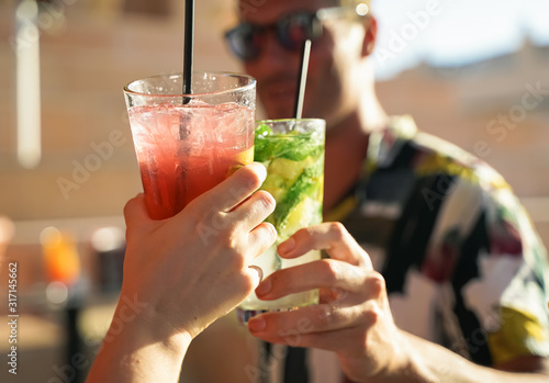 Happy friends having a party drinking cocktails. Fashionable teenagers celebrating holiday. Hands and cocktails. Party, holiday and summer concept. Focus on the hand.