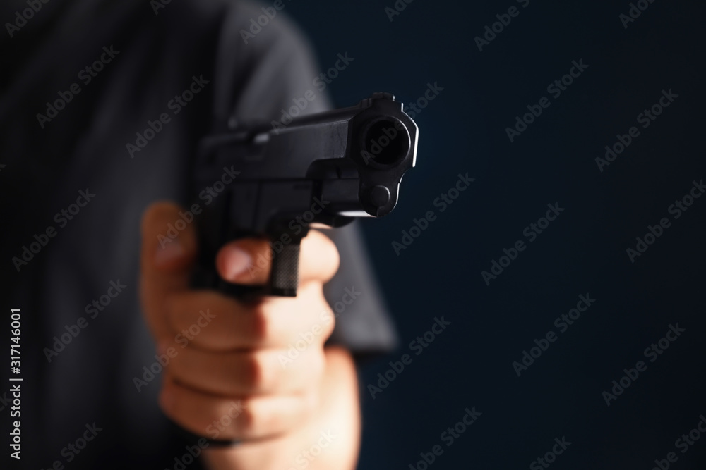 Man holding gun on dark background, closeup Man holding gun on dark background, closeup