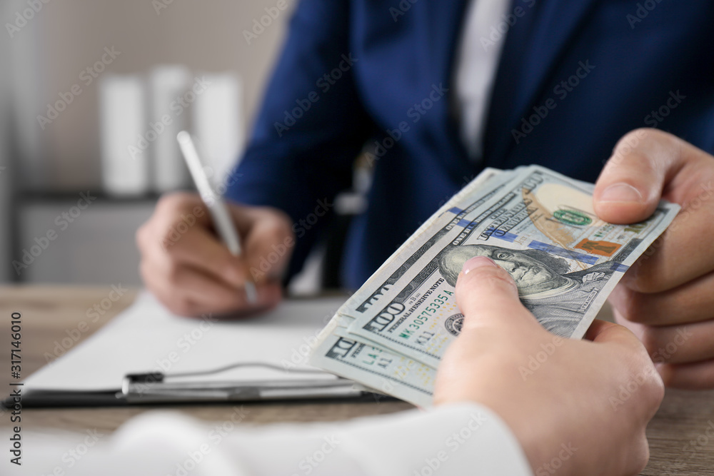 Woman giving bribe to man at table in office, closeup Woman giving bribe to man at table in office, closeup